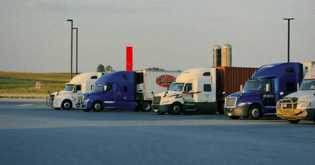 Row of semi trucks parked at a transportation company lot