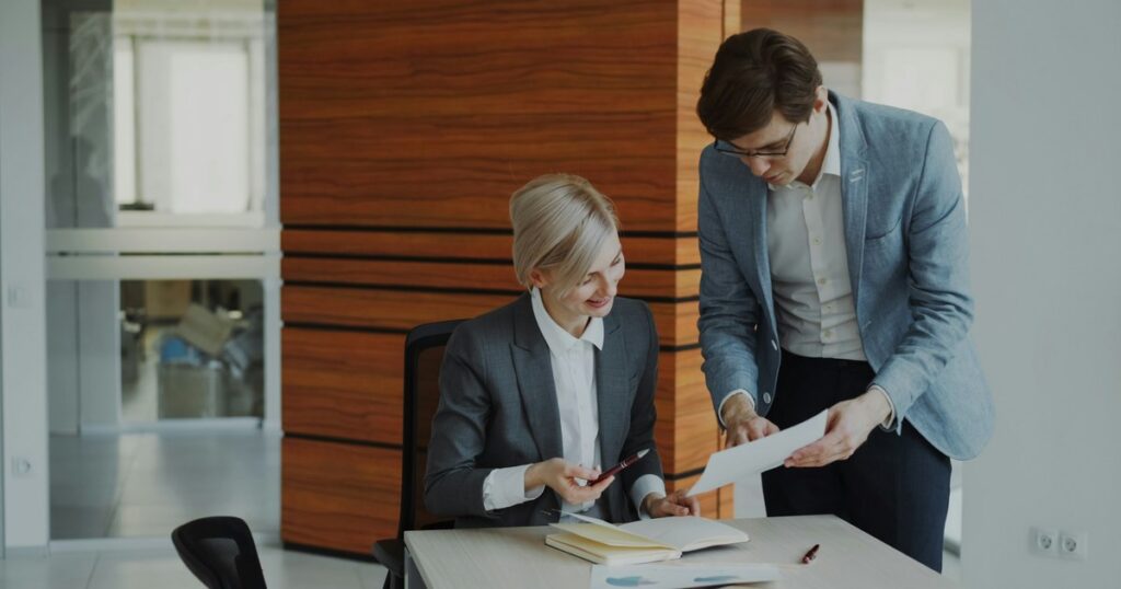 Two insurance agency colleagues reviewing documents together at an office desk